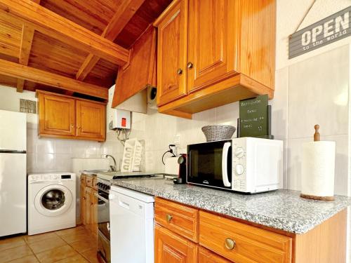 a kitchen with wooden cabinets and a microwave at Casa São Sebastião - Casas BemHaja in São Miguel de Acha