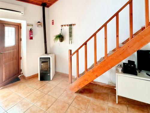 a living room with a staircase and a tv at Casa São Sebastião - Casas BemHaja in São Miguel de Acha