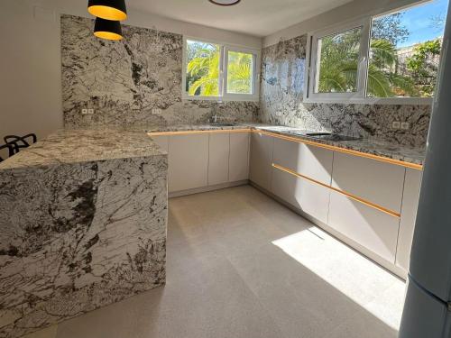 Una cocina con encimeras de mármol y gabinetes y ventanas blancos. en Asia Gardens Villa with private pool in Benidorm, en Cala de Finestrat