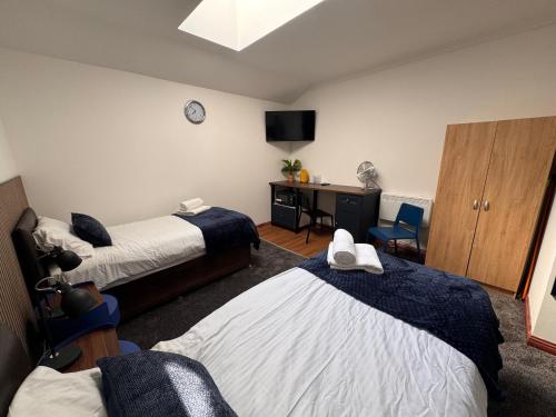 a room with two beds and a desk with a tv at Core Citi Lets, Guild Street Rooms in Aberdeen