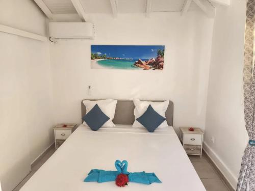 een slaapkamer met een wit bed met een blauwe strijkplank bij Bungalow confortable à Le Gosier - 20 m² avec jardin in Mare Gaillard