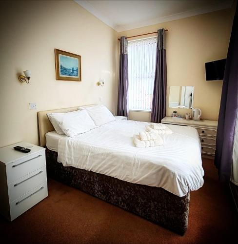 a bedroom with a bed with white sheets and a window at Viking Guest House in Bridlington