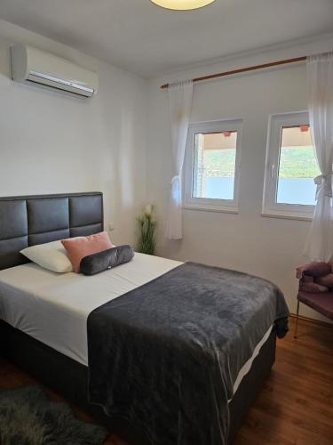 a bedroom with a large bed and two windows at Vila Tea in Korčula