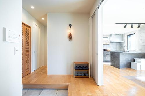 a kitchen with white walls and a wooden floor at 海まで徒歩7分庭とデッキでくつろぐ大人葉山の上質ステイ in Hayama