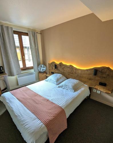a bedroom with a large bed with a wooden headboard at Hotel le Chasseur in Illkirch-Graffenstaden