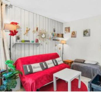 a living room with a red couch and a table at au Bonheur - Praloup 1600 - Au cœur de la station et au pied des pistes - La voile des neiges - parking commun privé - local ski in Pra-Loup