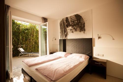 a bedroom with a bed and a large window at Holiday Apartments - Camping Al Porto in Nago-Torbole