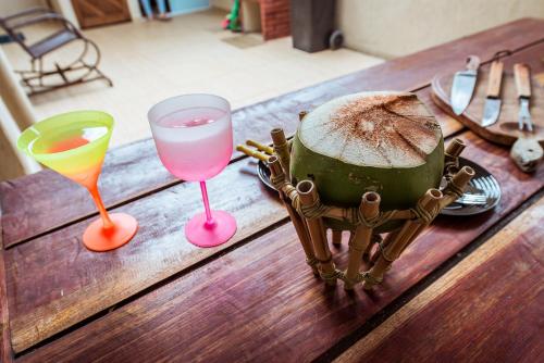 a wooden table with two glasses and a cake on it at Casa em Jacuma, com piscina, 5 suites e fliperama in Jacumã