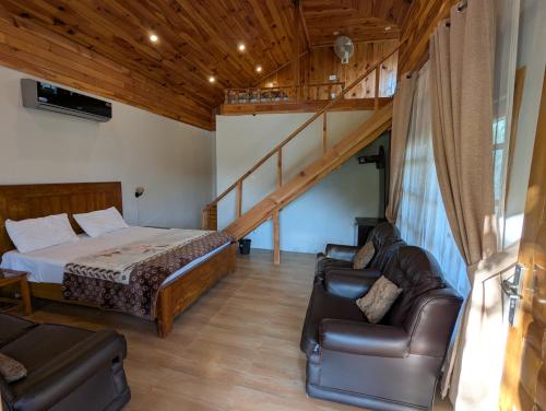 a bedroom with a bed and a couch and a staircase at Attic Cottage - Country Club Resorts Balakot in Bālākot