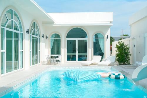 Eine Frau, die in einem Schwimmbad in einem Haus liegt. in der Unterkunft White Heaven Pool Villa Pattaya in Ban Nong Chaeng