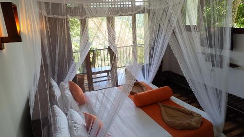 a bedroom with a bed with white curtains and a window at Ameliora Hotel Ella in Ella