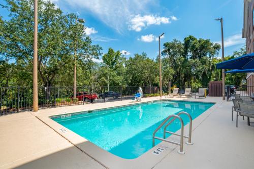 a swimming pool with chairs and a umbrella at Comfort Suites Tallahassee Capitol - University Area in Tallahassee