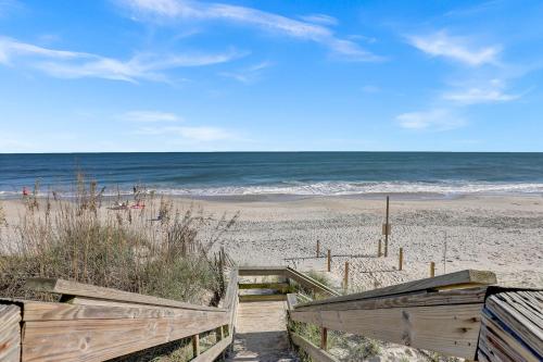 a beach with a wooden staircase leading to the ocean at Walk to everything, 360 views, elevator, fence in Surf City