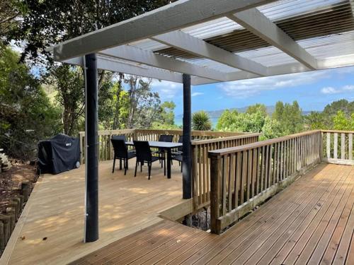 a patio with a table and chairs on a deck at Bush & Bay Hideaway in Cable Bay