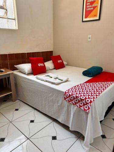 a bed with red and white pillows on it at OYO Pousada Paraná, Cuiabá in Cuiabá