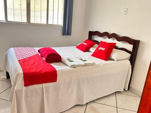 a bed with red and white pillows on it at OYO Pousada Paraná, Cuiabá in Cuiabá