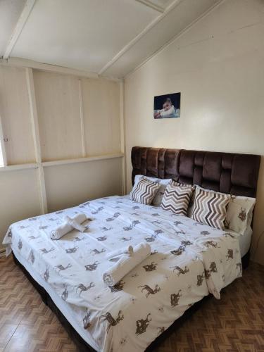 a bedroom with a large bed with a brown headboard at guyville house in Temara