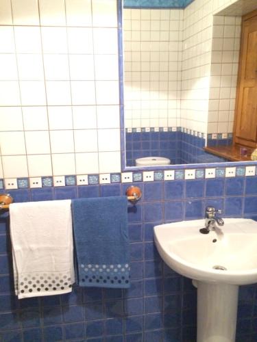 a blue tiled bathroom with a sink and a mirror at La casina de Berdayes in Labra