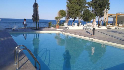 a woman standing next to a swimming pool next to the water at B&B Do'mmilio in Crotone