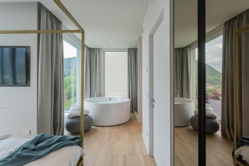 Un dormitorio con dos bañeras y una gran ventana. en Valarin Elite Lake Villa by Rentallcomo, en Vercana