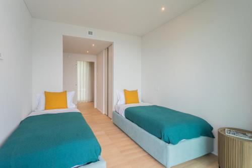 2 camas en una habitación blanca con naranja y verde en Valarin Elite Lake Villa by Rentallcomo, en Vercana