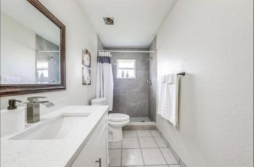 a white bathroom with a toilet and a sink at Downtown Lake Worth Retreat in Lake Worth Corridor