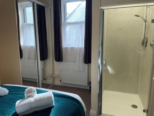 ein Badezimmer mit Dusche und ein Bett mit Handtuch in der Unterkunft Mutiny House in Weymouth