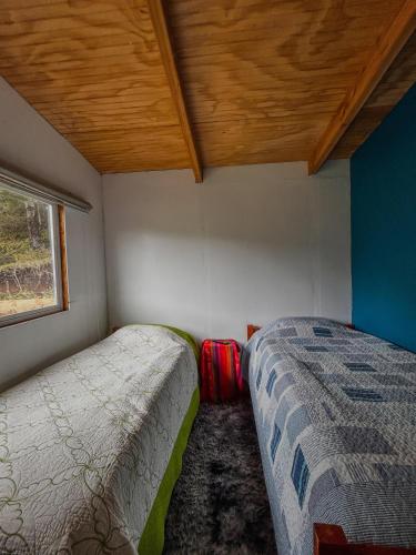 a small room with two beds and a window at refugio el bagual in Futaleufú