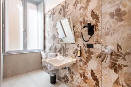 a bathroom with a sink and a mirror at Hotel Odeon Napoli in Naples