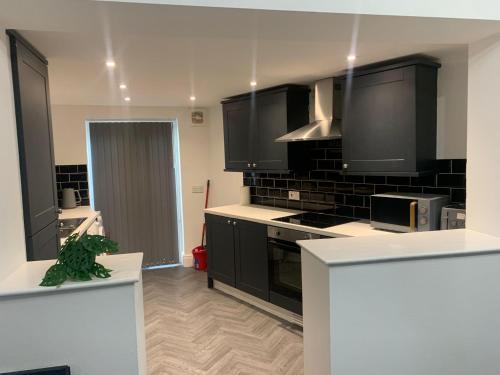 a kitchen with black cabinets and black appliances at A&A Luxury Stay Tunstall in Sunderland