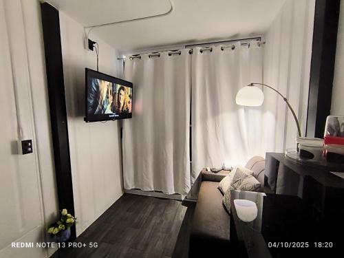 Una sala de estar con un televisor de pantalla plana en la pared. en Tucan container, en Tapantí