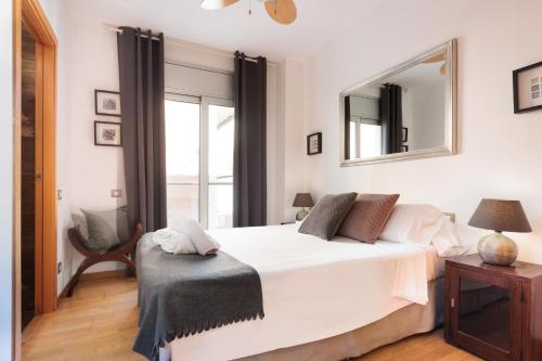 Un dormitorio con una cama blanca y un espejo. en Mar Bella Beach Apartments, en Barcelona