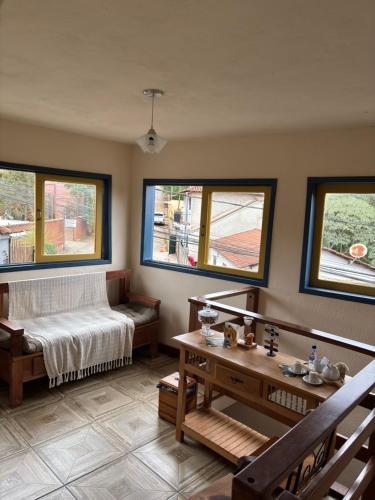 a bedroom with a bed and a table and windows at Astral de Minas in Tiradentes