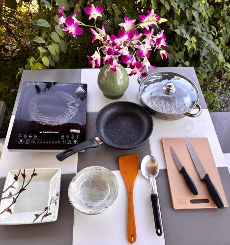 a table with utensils and a pan and a vase with flowers at Lalaland CD in Ban Mae Khon