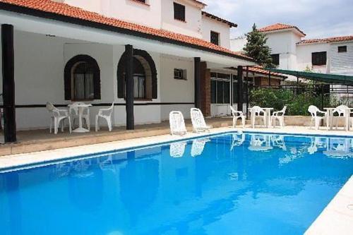 ラ・ファルダにあるHotel sol y sierrasの白い椅子付きの大型スイミングプール、建物