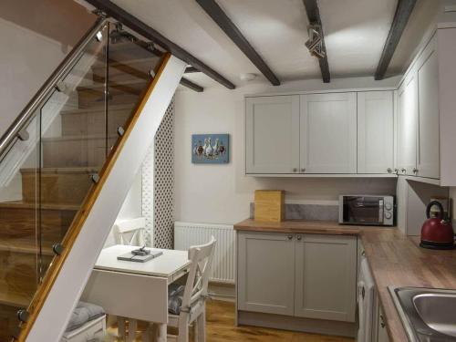 a kitchen with white cabinets and a table and a staircase at Stone Cottage in Wirksworth near Peak District in Wirksworth