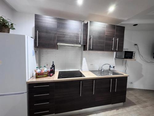 a kitchen with wooden cabinets and a sink and a refrigerator at Costa Libertad, Mesa del mar in Tacoronte