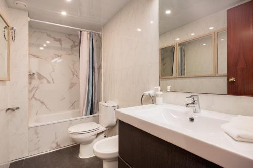 Un baño blanco con inodoro y lavabo. en Portal Del Angel Barcelona Apartment, en Barcelona