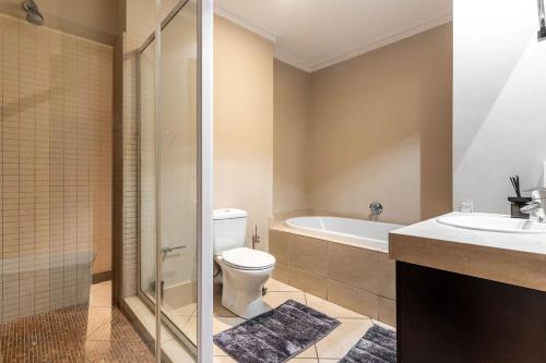 a bathroom with a toilet and a tub and a sink at 705 Icon Luxury Apartments in Cape Town