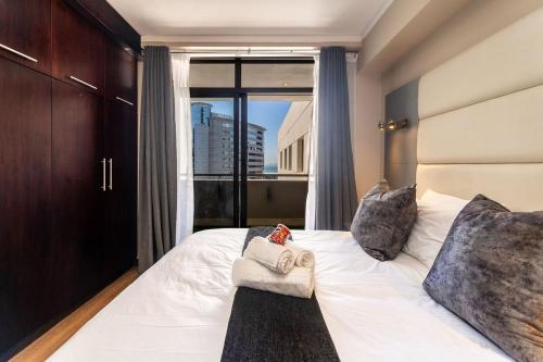 a bedroom with a large white bed with a window at 705 Icon Luxury Apartments in Cape Town