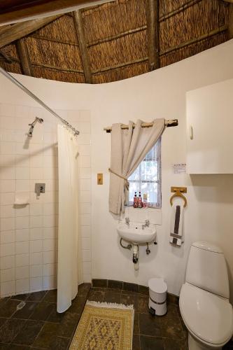 a bathroom with a sink and a toilet and a window at Mokolodi Backpackers - Relax in Nature near Gaborone with Pool, Fast WiFi, Coworking Space & Garden Chalets - Tranquillity Redefined in Gaborone