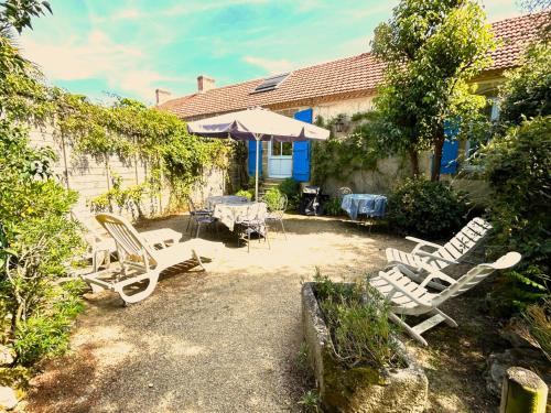 a group of chairs and an umbrella in a yard at Demeure François de l'Isle du Fief - Charme unique in La Barre-de-Monts