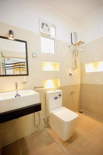 ein Badezimmer mit Toilette, Waschbecken und Spiegel in der Unterkunft White Horse in Hikkaduwa
