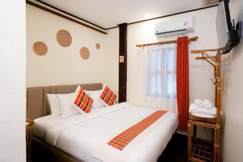 a bedroom with a large white bed and a window at Sarana Guest House in Luang Prabang