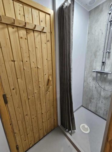 a shower stall with a wooden door in a bathroom at Villa Blackberry, nära Kolmården & Norrköping in Åby