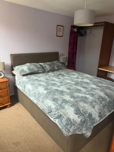 a bedroom with a bed with a blue comforter at Holly cottage in Catfield