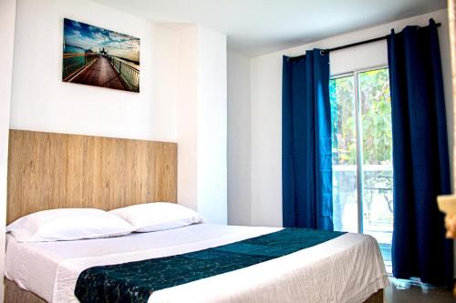 ein Schlafzimmer mit einem Bett mit blauen Vorhängen und einem Fenster in der Unterkunft Hotel Grand Rodadero Horizon Santa Marta in Santa Marta