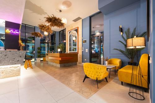 a lobby of a store with yellow chairs and tables at Invictus Hotel in Budva