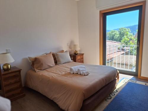 ein Schlafzimmer mit einem großen Bett mit einem großen Fenster in der Unterkunft Casa Feixa Gerês in Lordelo