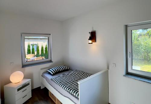 Un dormitorio pequeño con una cama y dos ventanas. en Haus am See, en Franzensberg